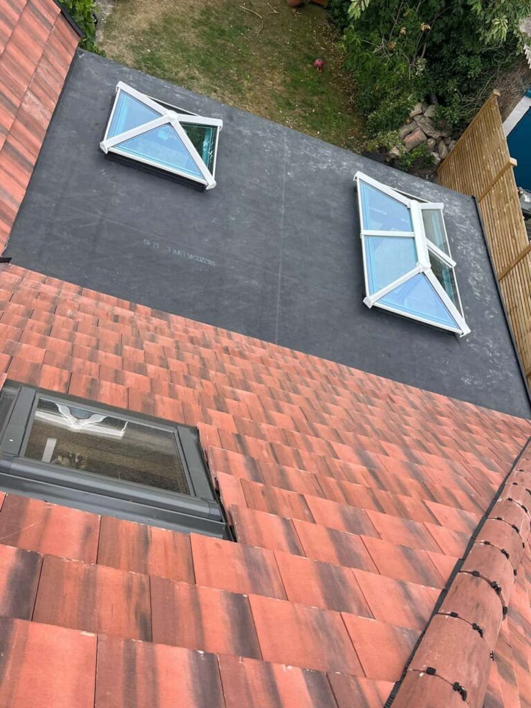 This is a photo taken from the roof ridge looking down a tiled pitched roof on to a flat roof. Works carried out by LS Roofing Woodley